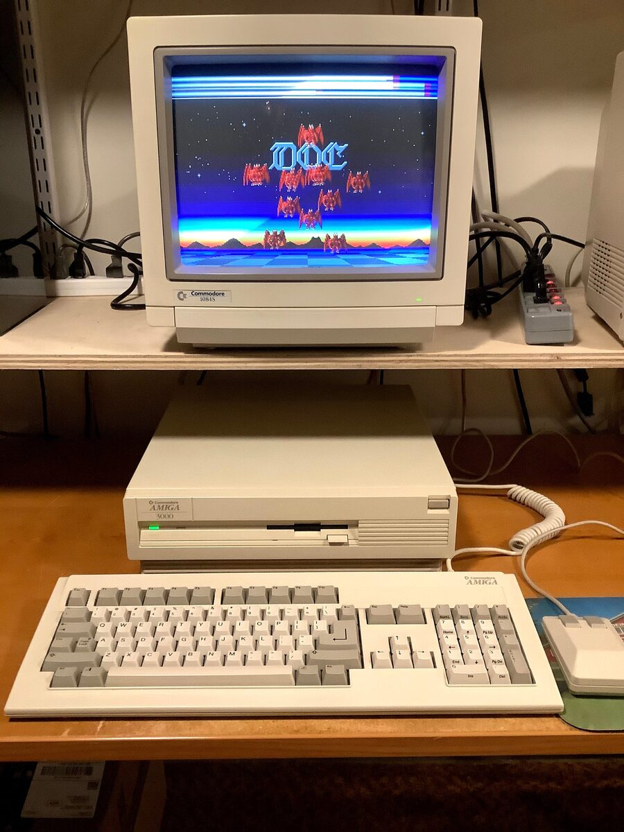 Amiga 3000 with keyboard and mouse under a Commodore 1084S monitor showing a demo with a copper sky