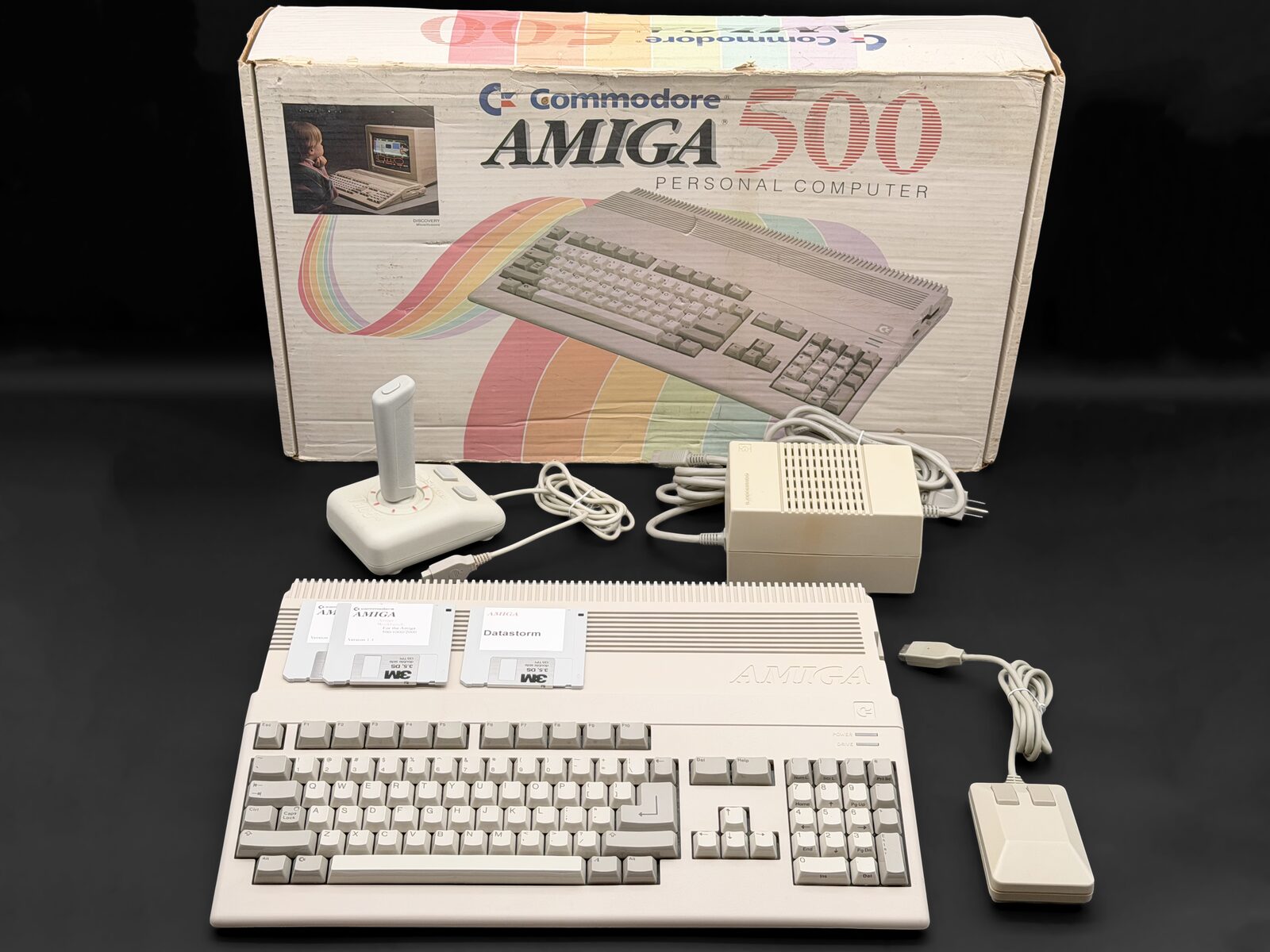 Early Amiga 500 in front of its original box with joystick, mouse and power supply